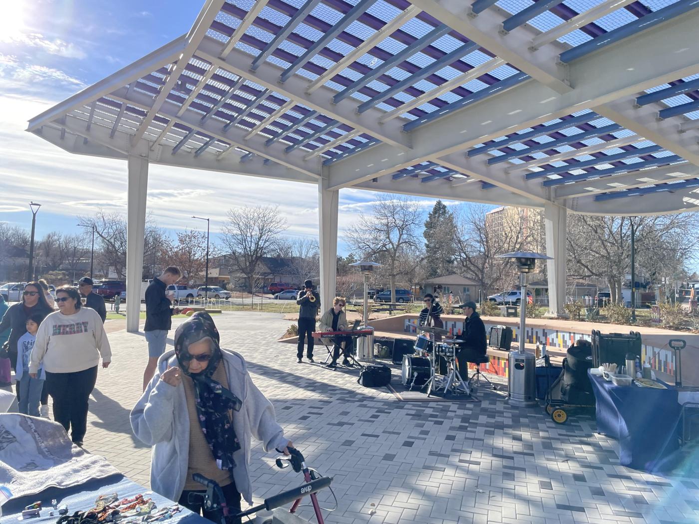 Neighbors walk around Joe P Martinez Park at the Villa Park Winter Festival while a jazz band plays in the background in Villa Park, Denver